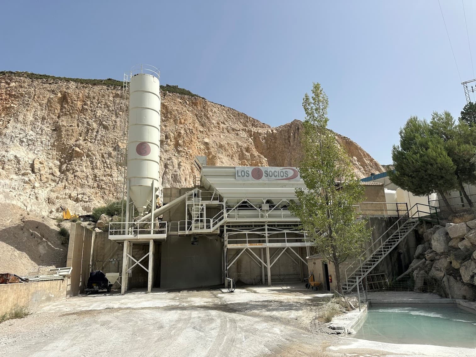 Instalaciones industriales Los Socios con un silo blanco frente a una gran montaña rocosa.